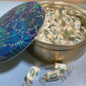 opened Holiday Mellow Mint Tin with loose taffy kisses in front